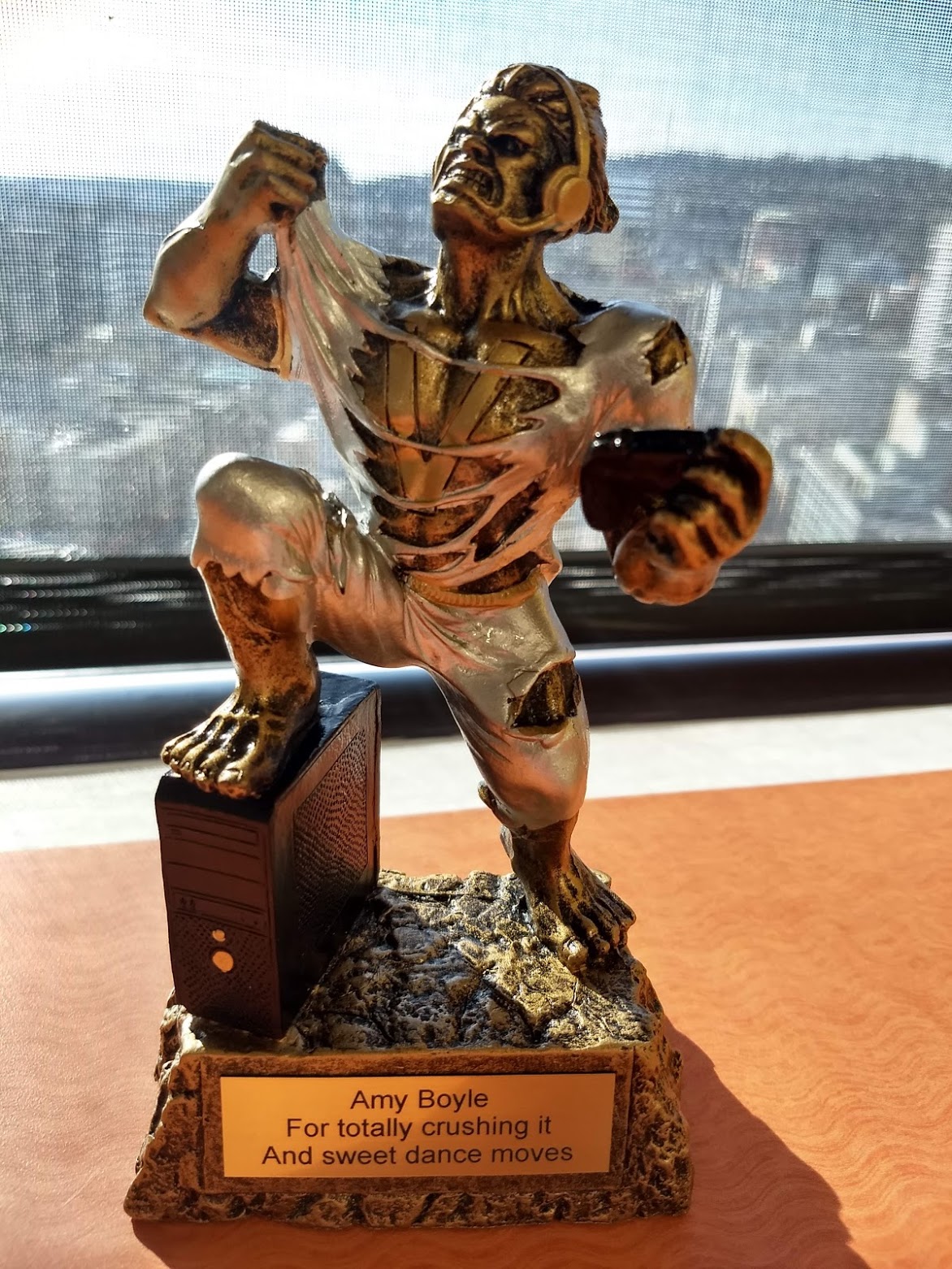 Trophy of person in a lunge on a computer tower while shredding off their shirt. The plaque reads For totally crushing it and sweet dance moves